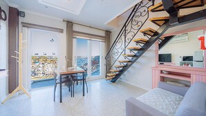 Een woonkamer met een trap, een eethoek en een balkon met uitzicht.
