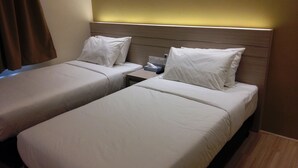 A hotel room with two single beds, each with white linens and pillows, a bedside table with a remote control, and a wall-mounted light. - Star Tree Homestay (Kuantan)