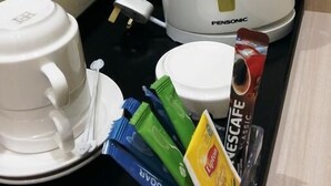 A coffee station with a white coffee maker, a cup, and sugar packets on a tray. - Star Tree Homestay (Kuantan)