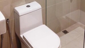 A modern bathroom with a glass-enclosed shower, a toilet, and a towel rack with folded towels. - Star Tree Homestay (Kuantan)