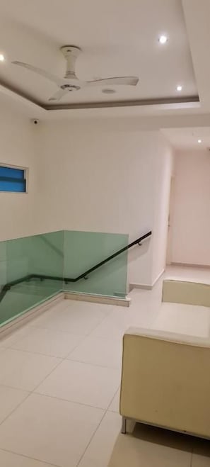 A hotel room with a ceiling fan, a glass staircase, and a bed. - Star Tree Homestay (Kuantan)