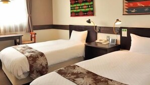 A hotel room with two beds, a nightstand, a lamp, and a window with curtains. - Matsumoto Tourist Hotel (Matsumoto)