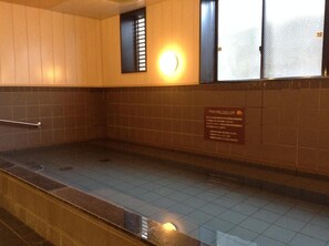 A tiled bathroom with a handrail, a wall-mounted light, and a sign with text. - Matsumoto Tourist Hotel (Matsumoto)
