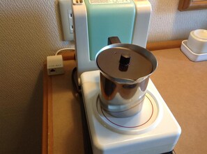 A portable electric kettle on a white base with a power cord plugged in. - Matsumoto Tourist Hotel (Matsumoto)