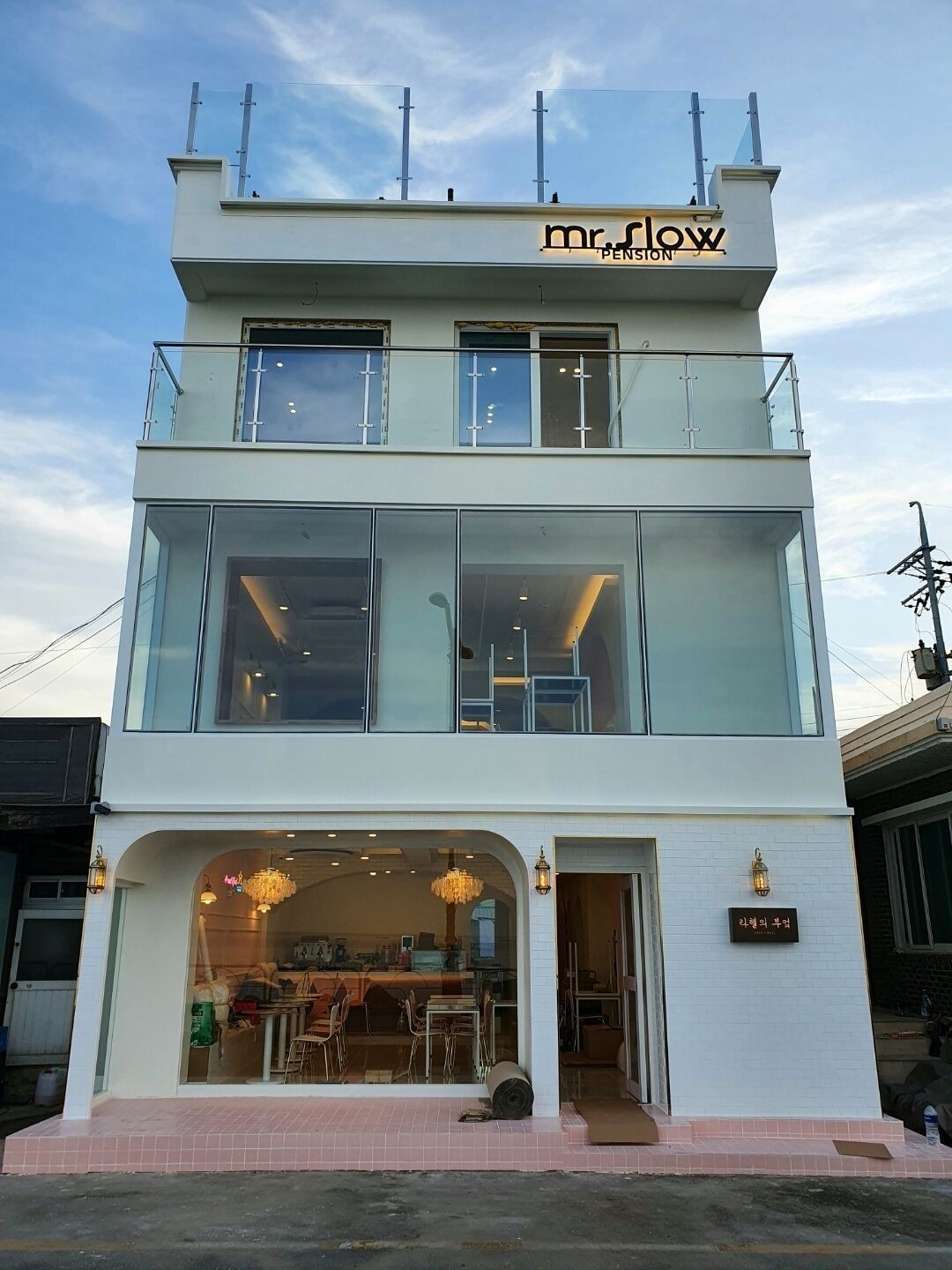A two-story building with a glass facade, a sign reading "Mr. Flow Penston," and a visible entrance with a chandelier.