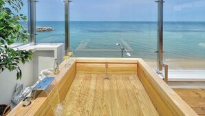 A wooden bathtub with a glass enclosure overlooking a beach. - Mr. Slow (Sokcho)