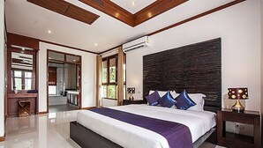 A modern bedroom with a large bed, a desk, and a bathroom visible through an open door. - NB Villa Sienna (Koh Samui)