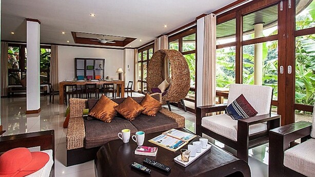 A spacious living area with a sofa, armchairs, a coffee table, and a dining area in the background. - NB Villa Sienna (Koh Samui)