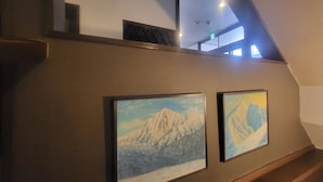 A staircase with framed paintings of mountains. - Hakuba Powder Lodge (Hakuba)