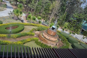 A landscaped garden with a central fountain, surrounded by neatly trimmed hedges and various tropical plants. - Phudara Resort (Phu Ruea)
