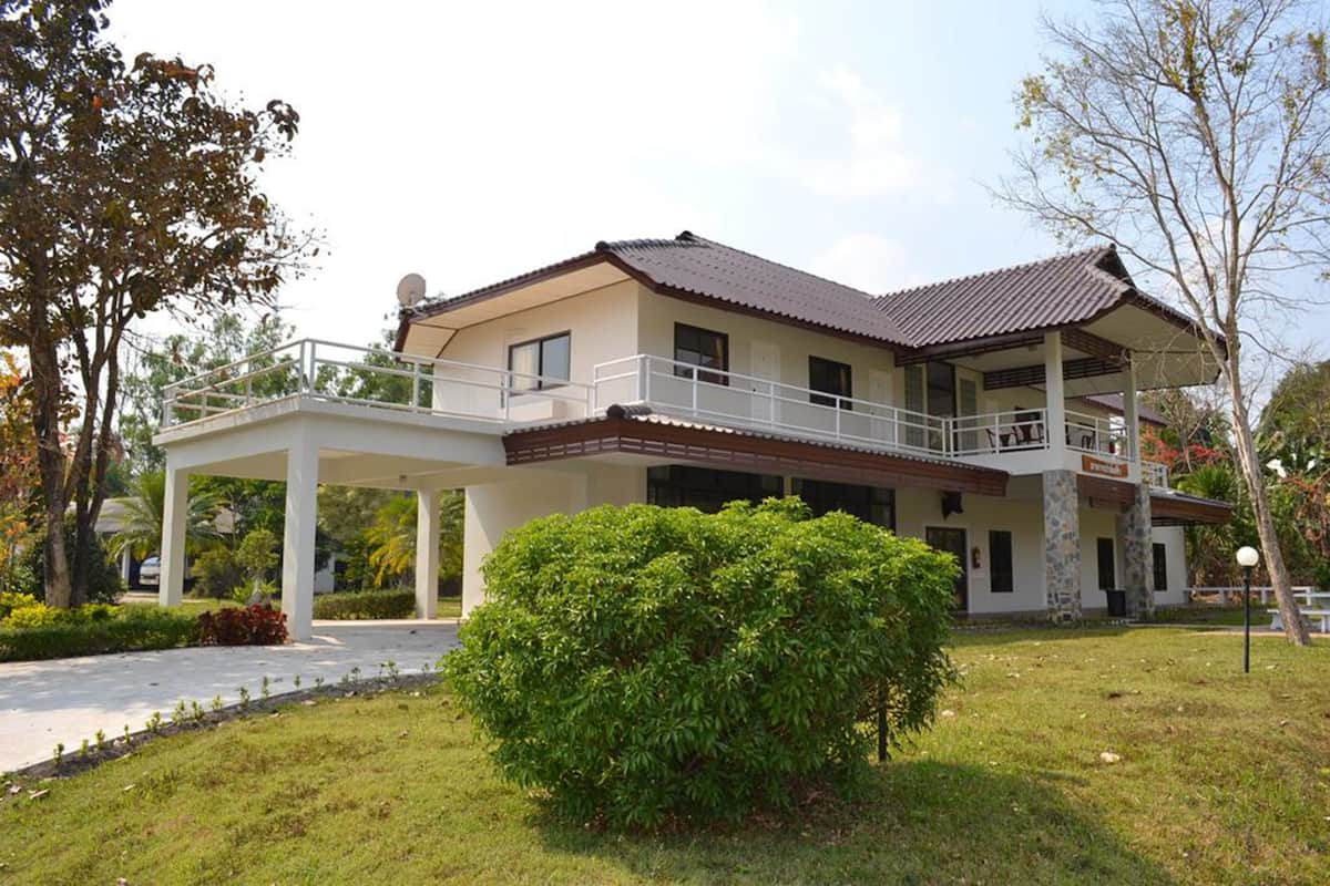 A two-story house with a covered patio and a small garden.