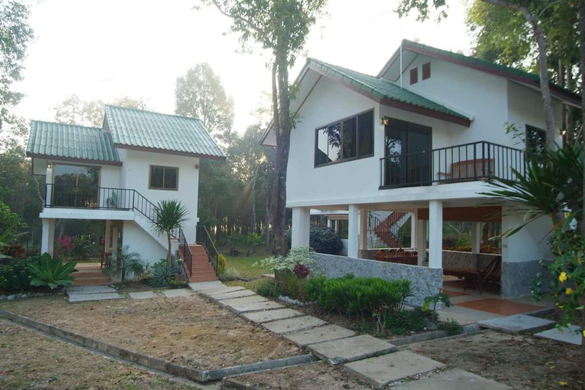 A two-story house with a balcony, a staircase, and a garden with various plants.