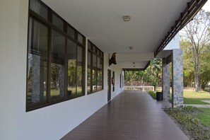 A covered corridor with large windows, stone pillars, and a view of the outdoors.