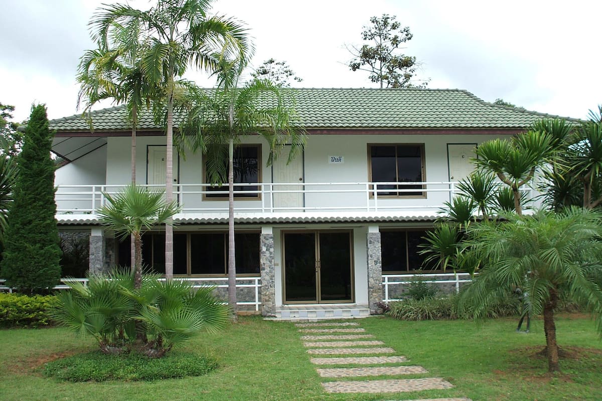 A two-story building with a tiled roof, a balcony on the upper floor, and a front entrance with glass doors.