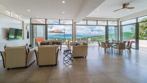 A spacious living area with a large window offering a view of the ocean and mountains.