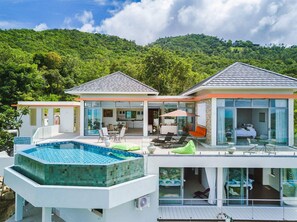 A modern two-story house with a swimming pool, large glass windows, and a view of a forested hill. - NB Villa Ying Yang (Koh Samui)