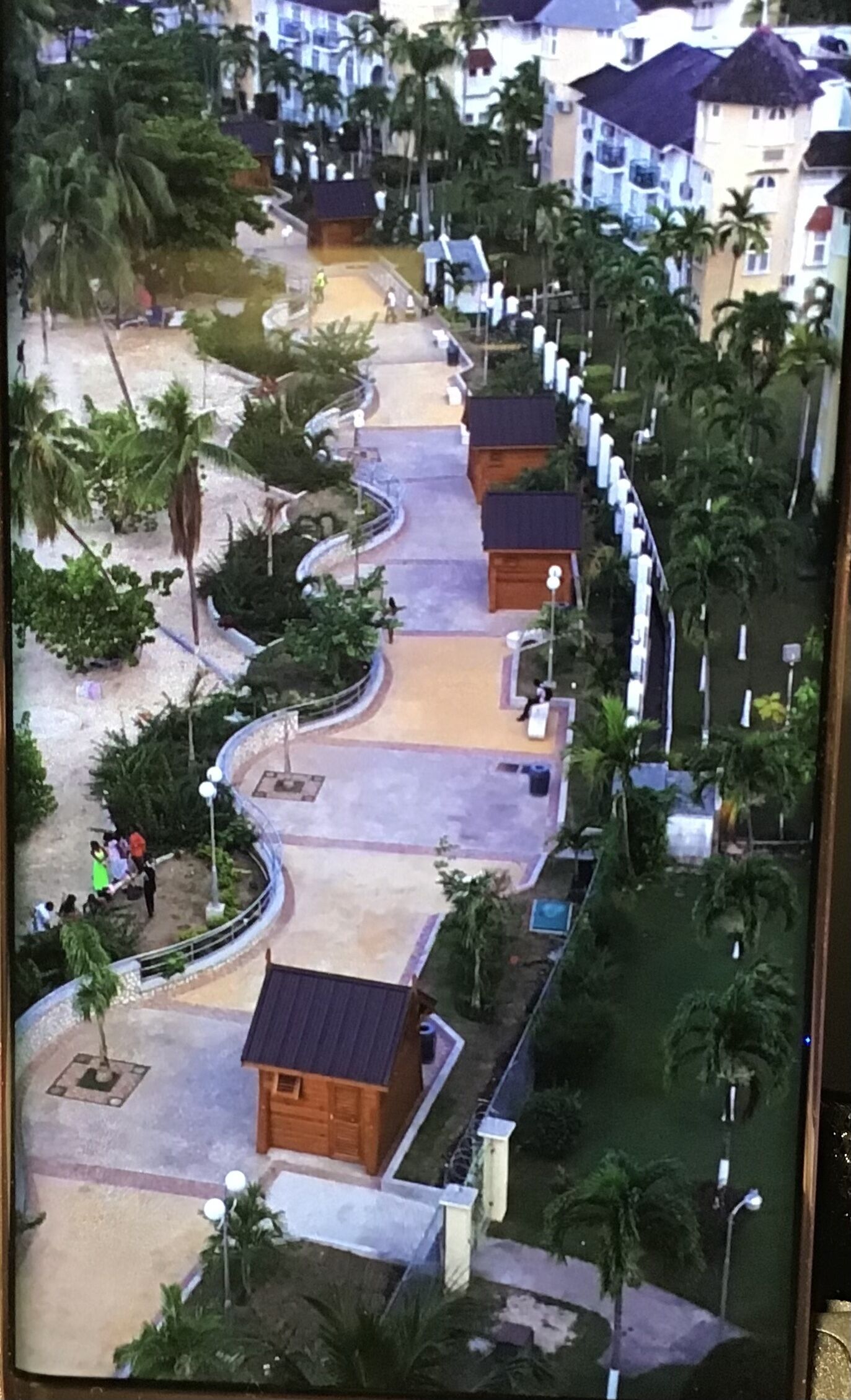 Un complexe hôtelier doté d’une allée centrale, de palmiers et de petits chalets en bois.