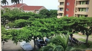 A residential area with multi-story buildings, parked cars, and lush greenery. - The McFarlane's Place is right in the heart of Ocho Rios Jamaica. (Ocho Rios)