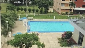 A swimming pool with a fenced area, lounge chairs, and a building in the background. - The McFarlane's Place is right in the heart of Ocho Rios Jamaica. (Ocho Rios)