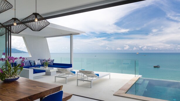 Un área lounge exterior moderna con piscina, asientos y vista al mar.