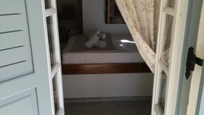 Una stanza con un letto a castello, una piccola finestra con tende e un pavimento in legno.