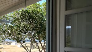 Una stanza con una grande finestra, una panca in pietra e vista su un albero e edifici in lontananza.