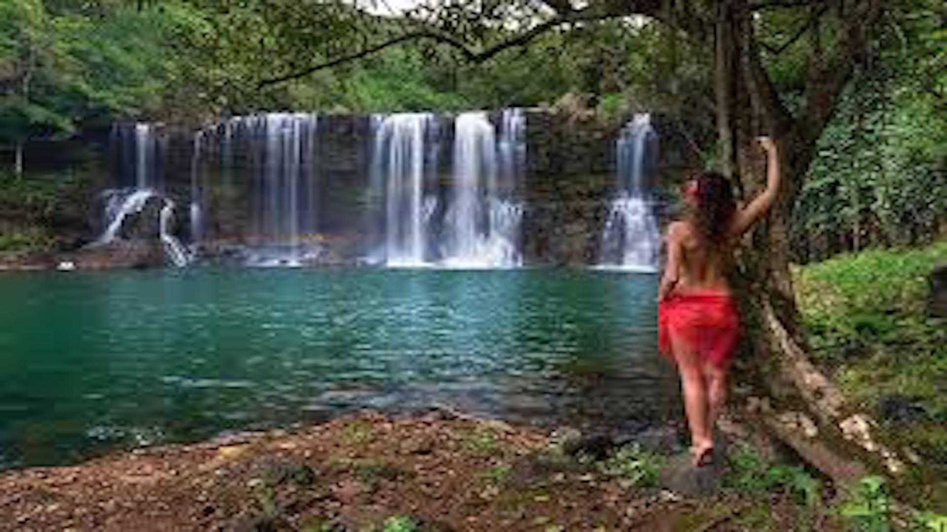 A waterfall with multiple cascades over a body of water, surrounded by greenery.