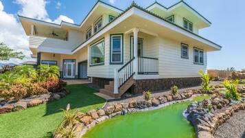 Une maison à deux étages, avec des fondations en pierre, une piscine verdoyante et une pelouse bien entretenue.