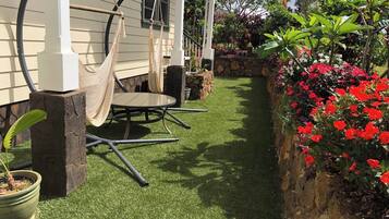 Une terrasse avec une table ronde et des chaises, un hamac et une plante en pot.