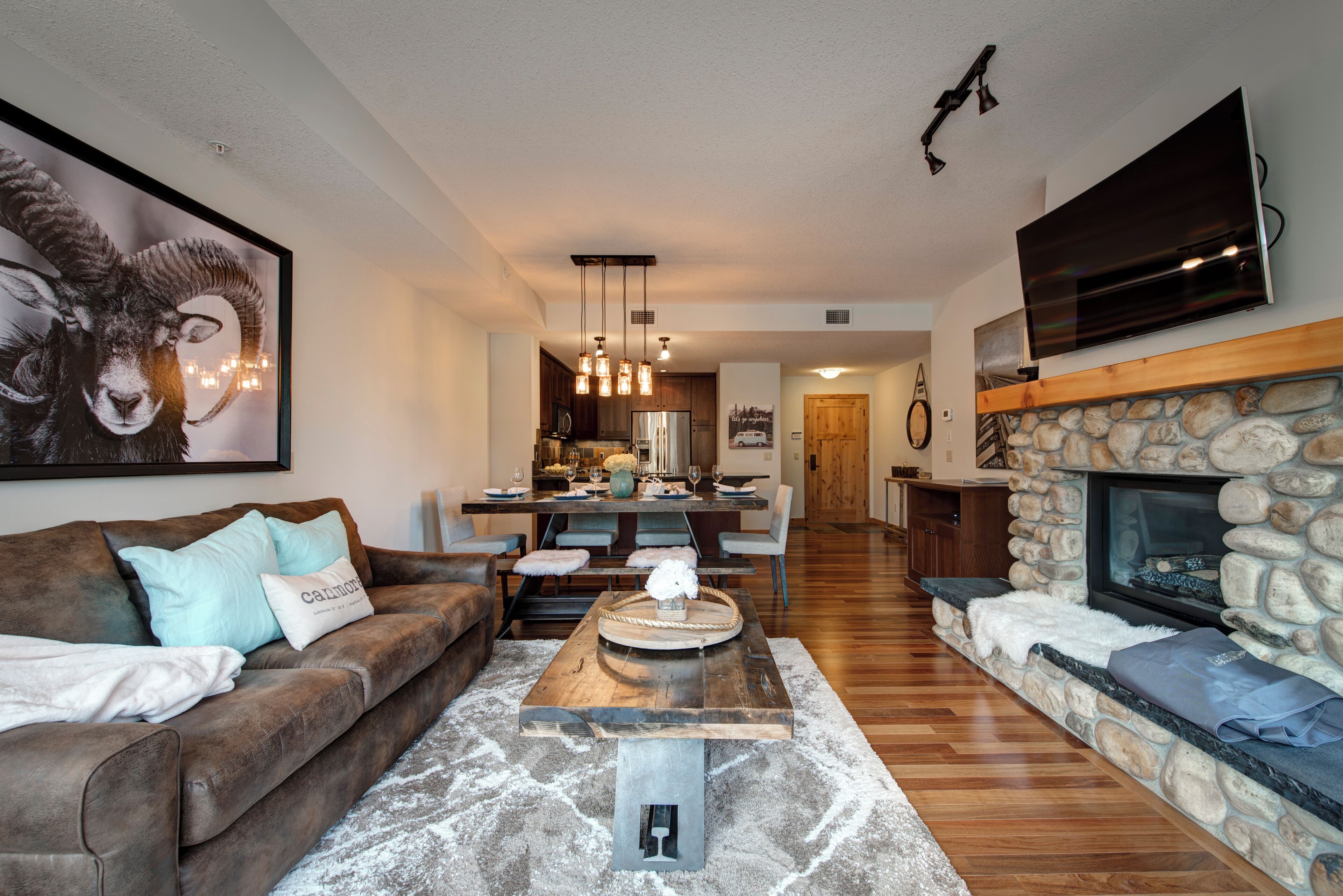 A living room with a brown couch, a coffee table, and a stone fireplace.