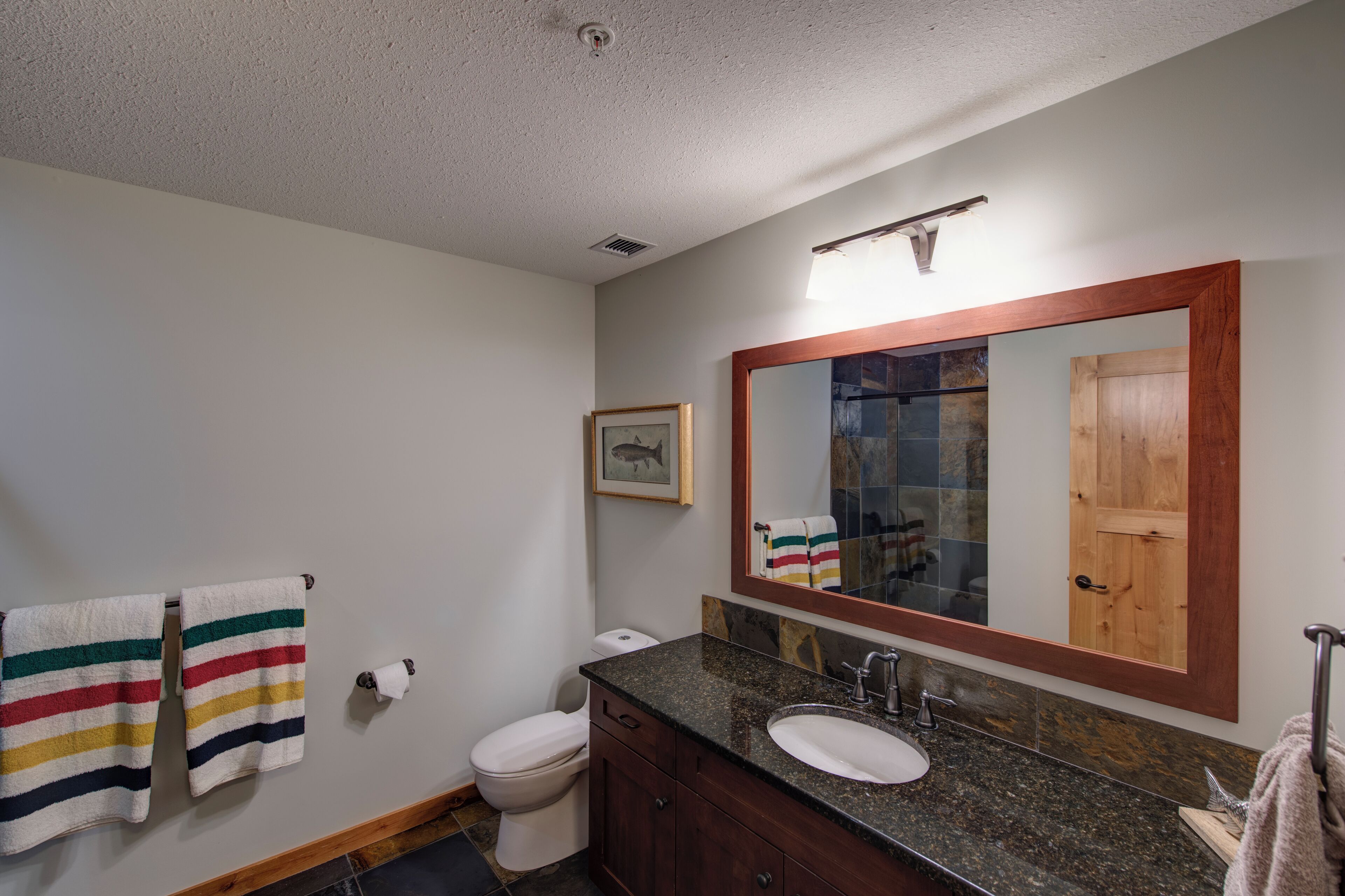 Une salle de bain équipée de toilettes, d’un lavabo, d’un miroir et de serviettes à rayures.