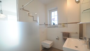 A modern bathroom with a white sink, a toilet, and a shower area.