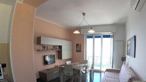 A compact living space with a kitchenette, dining area, and a sofa. - Arcobaleno Apartament  500 meters from the sea. (Albissola Marina)