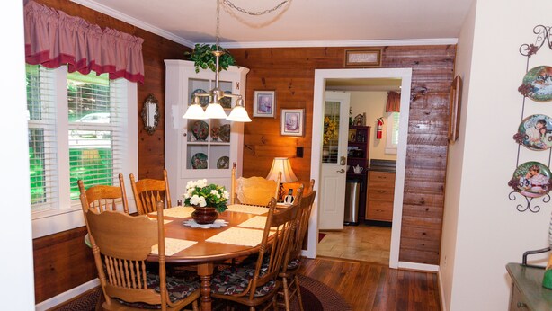 A dining room with a wooden table, chairs, and a chandelier. There is a window with blinds and a door leading to another room. - COMFORTABLE, HOMEY, FULLY RENOVATED MOUNTAIN COUNTRY COTTAGE (Jefferson)