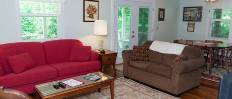 A living room with a red sofa, a brown sofa, a wooden coffee table, and a dining area with a table and chairs.