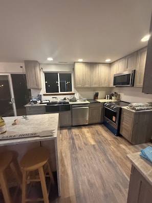 A modern kitchen with wooden cabinets, stainless steel appliances, and a bar area. - New Remodel! Waterfront, pets, Outdoor Ent, Hottub & Views 4min to Leavenworth. (Leavenworth)