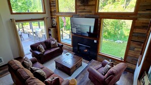 A spacious living room with a fireplace, large windows, and a view of the outdoors. - New Remodel! Waterfront, pets, Outdoor Ent, Hottub & Views 4min to Leavenworth. (Leavenworth)