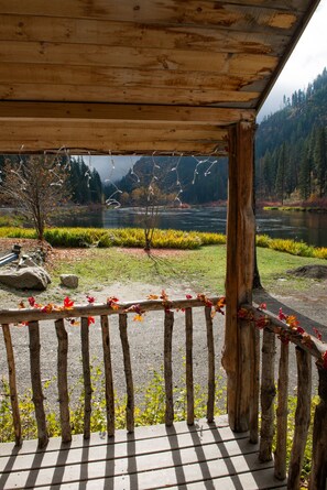 Relax on a shaded deck overlooking a serene river valley surrounded by dense forest.