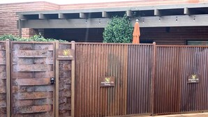 A gated entrance to Honeyguckle Villa with a brick wall and metal gate.