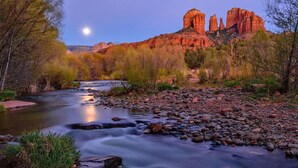 A river flowing through a rocky landscape with trees and a mountain range in the background.