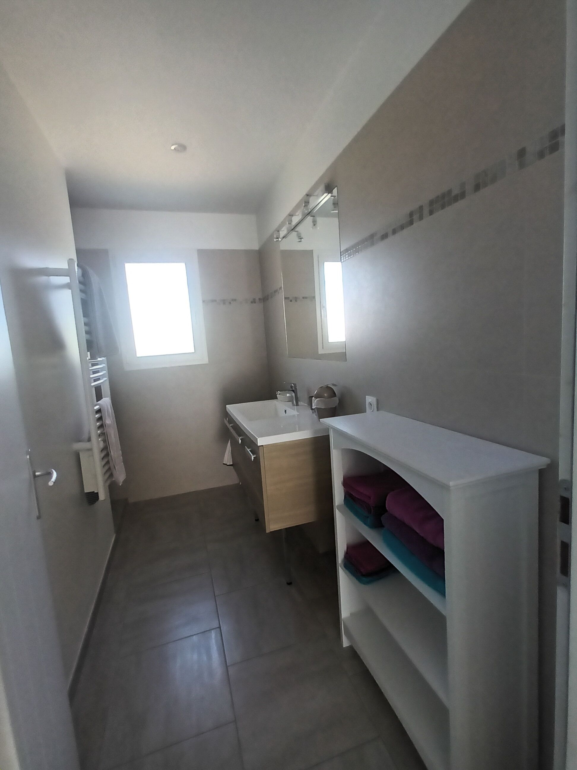 Une salle de bain moderne avec un grand miroir, un lavabo et un porte-serviettes.