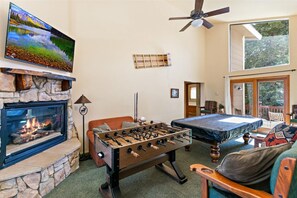 Ein gemütlicher Raum mit Kamin, Fußballtisch, Bett und Wandfernseher.