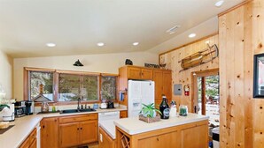 Eine Küche mit Holzausstattung, einem Kühlschrank, einer Spüle und einem Fenster mit Jalousien.