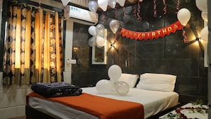 Una habitación de hotel con una cama, una mesita de noche y un ventanal con cortinas.