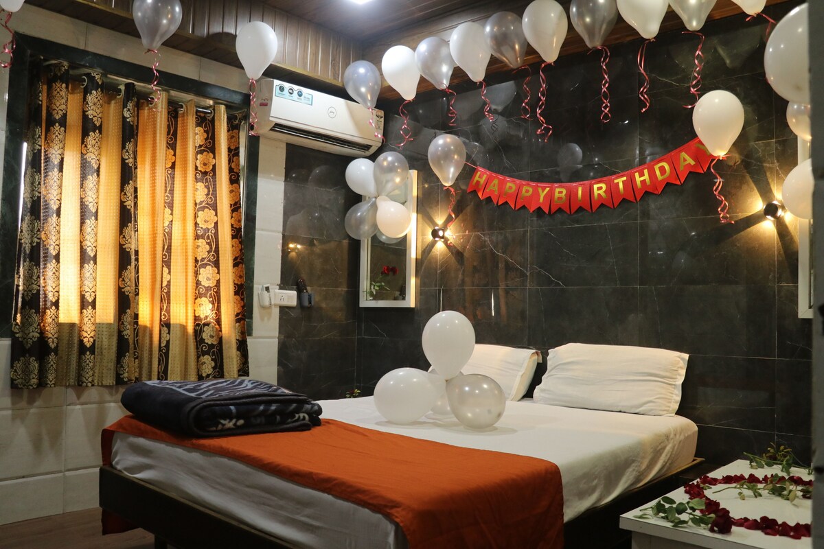 A hotel room with a bed, a bedside table, and a window with curtains.
