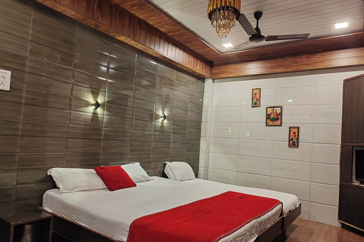A hotel room with a bed, wooden ceiling, and wall-mounted lights.