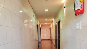 Un pasillo con paredes de baldosas blancas, suelo de madera y puertas a la derecha.