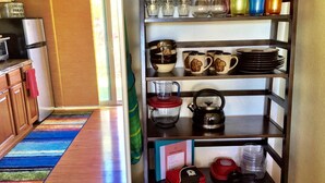 A kitchen with a refrigerator, a microwave, a shelf with glassware, mugs, and a kettle. - Enjoy viewing the photos of your Hale - home away from home (Waikoloa Village)