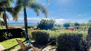 A patio with wicker furniture, a stone pathway, and a view of the ocean and distant landscape. - Enjoy viewing the photos of your Hale - home away from home (Waikoloa Village)