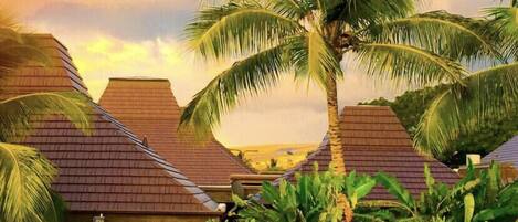 A tropical resort with multiple buildings, palm trees, and a variety of potted plants.
